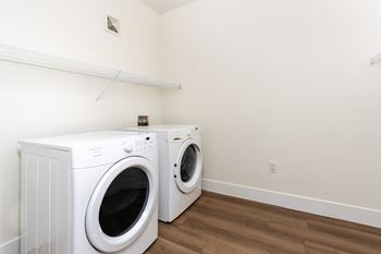 Two white front loading washing machines in a laundry room.